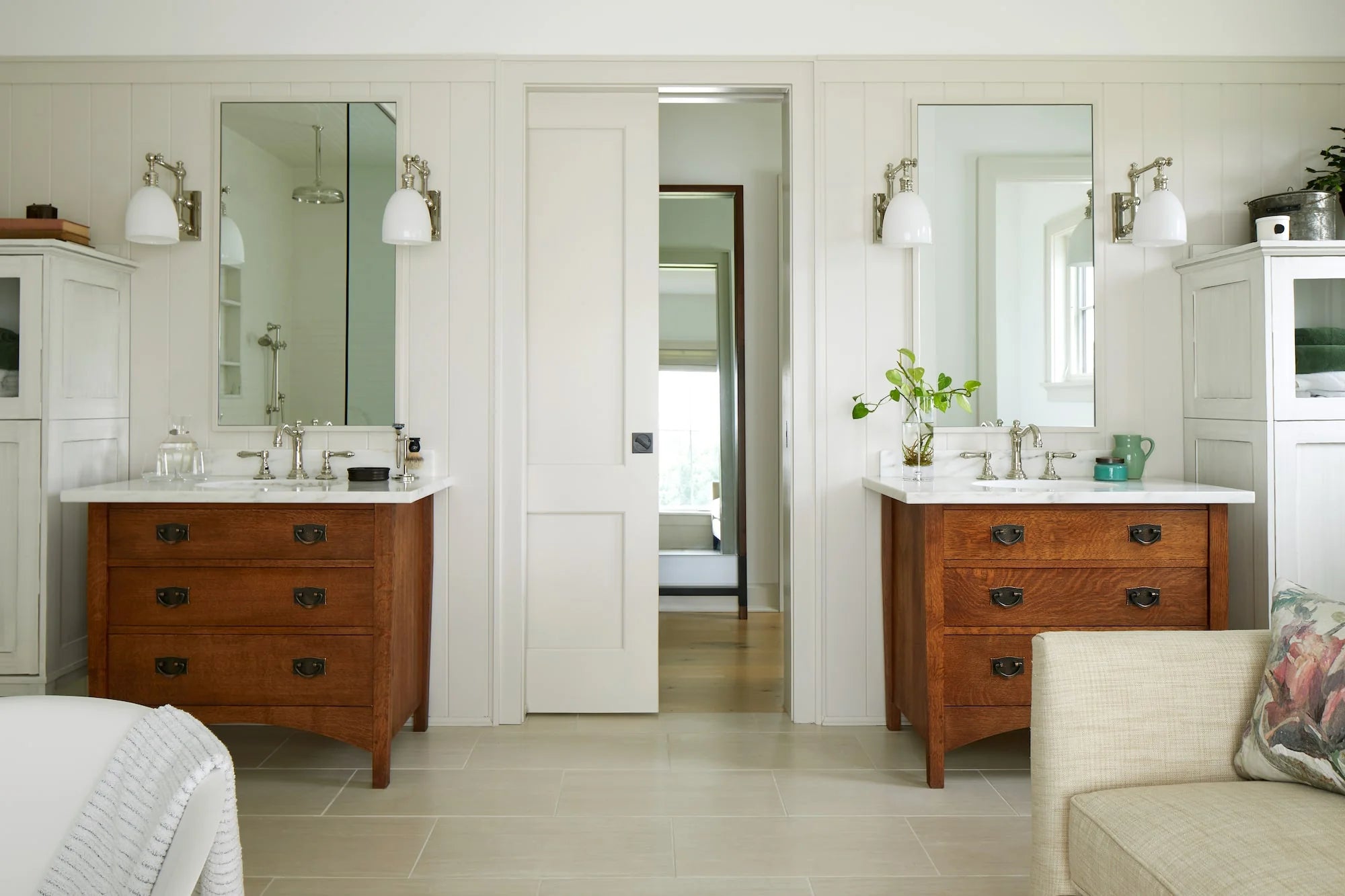 Cold Brook Farm bathroom with dual vanities in oak cabinetry, marble counters, farmhouse-style sconces, and white shiplap walls.