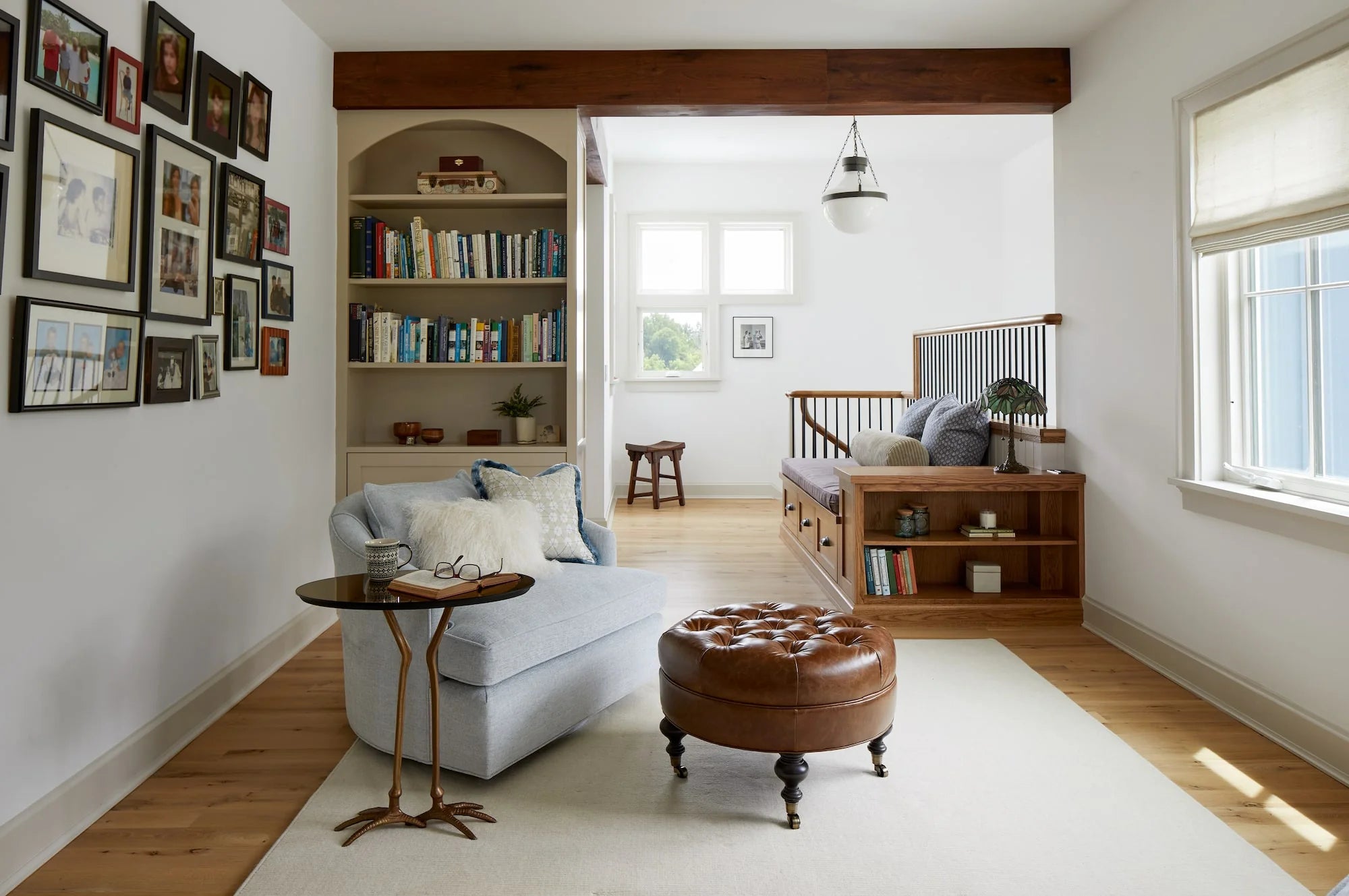 Cozy reading nook at Cold Brook Farm with built-in bookshelves, gallery wall of family photos, light-filled window seat, and warm wood flooring.