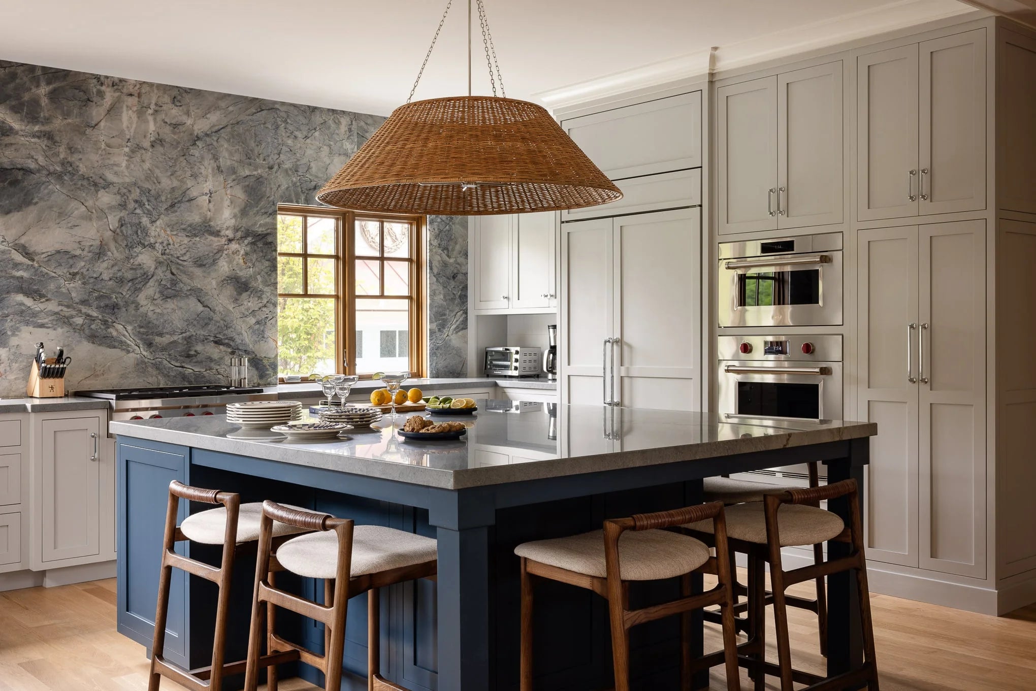Contemporary kitchen featuring gray cabinetry, navy island, and oversized woven pendant above quartz countertops.