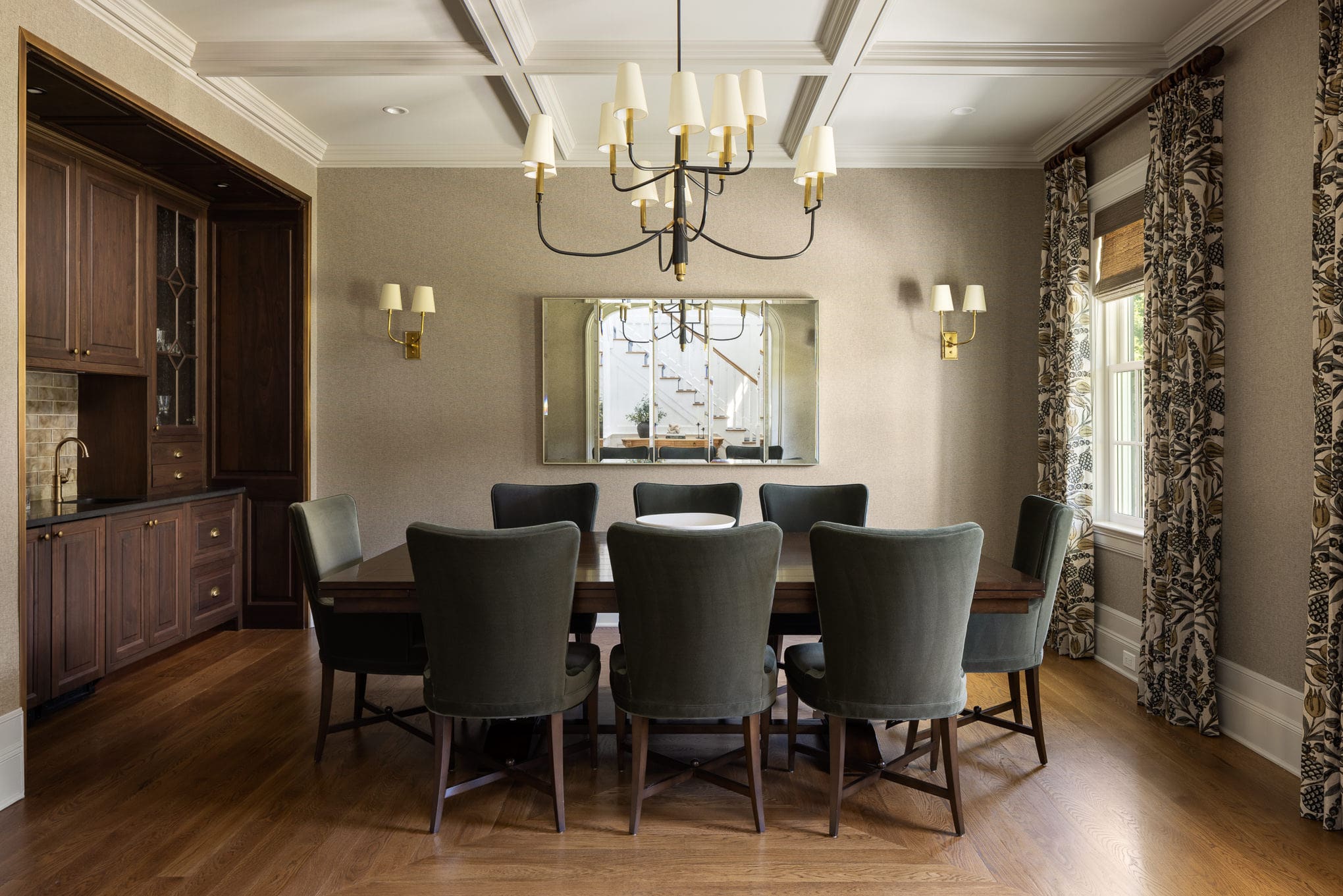 Formal dining room with dark wood table, green upholstered chairs, and gold chandelier at Moonlight project.