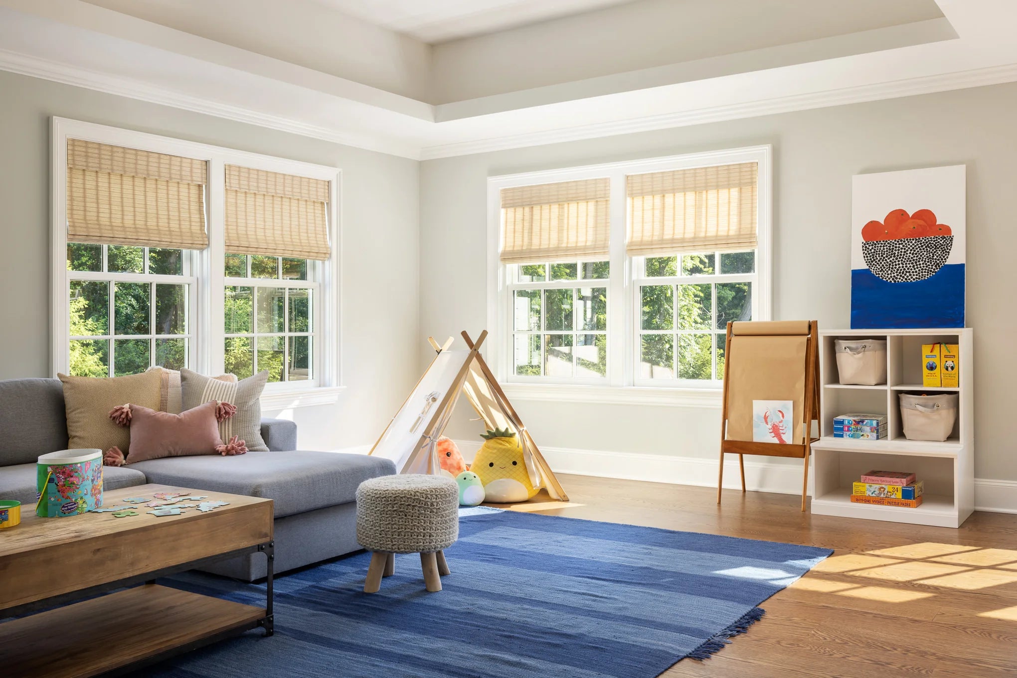 Playroom with tent, gray sectional, and natural light from large windows — Moonlight project.