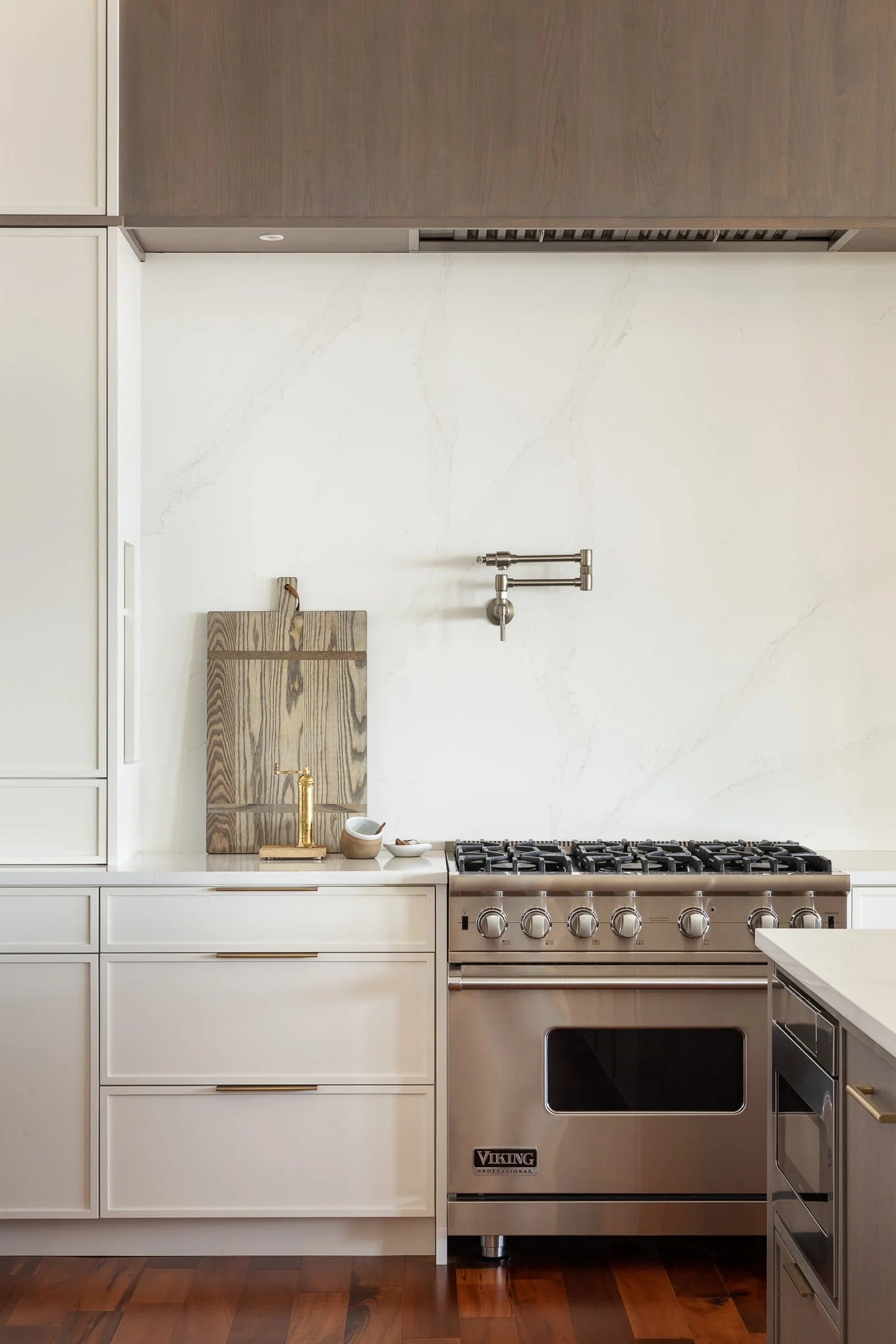 Viking stainless steel range with brass pot filler, white marble backsplash, and wood accents in luxury coastal kitchen – Haven Bay.