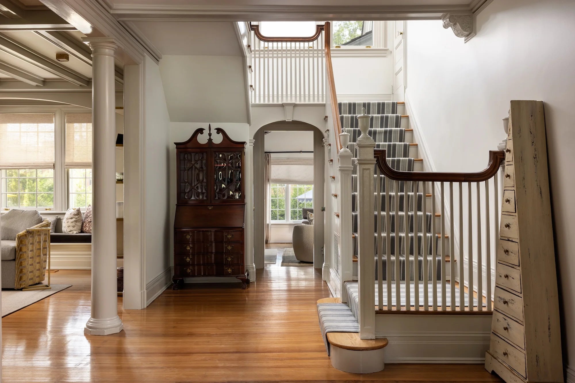 Stoneleigh historic home renovation in Westfield NJ by AHD&Co featuring white wood staircase with striped runner and antique furnishings.