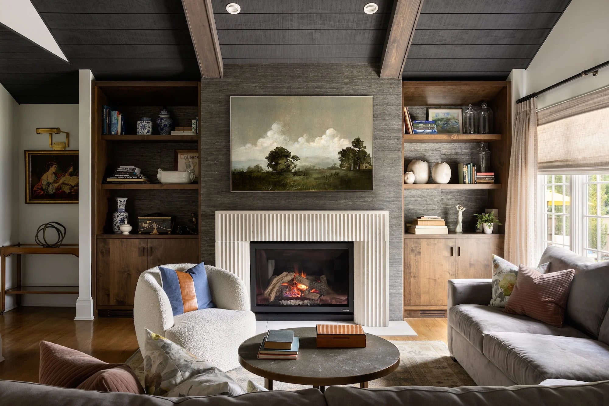 Stoneleigh family room renovation by AHD&Co featuring modern fireplace with fluted surround, built-in shelving, and layered contemporary decor.