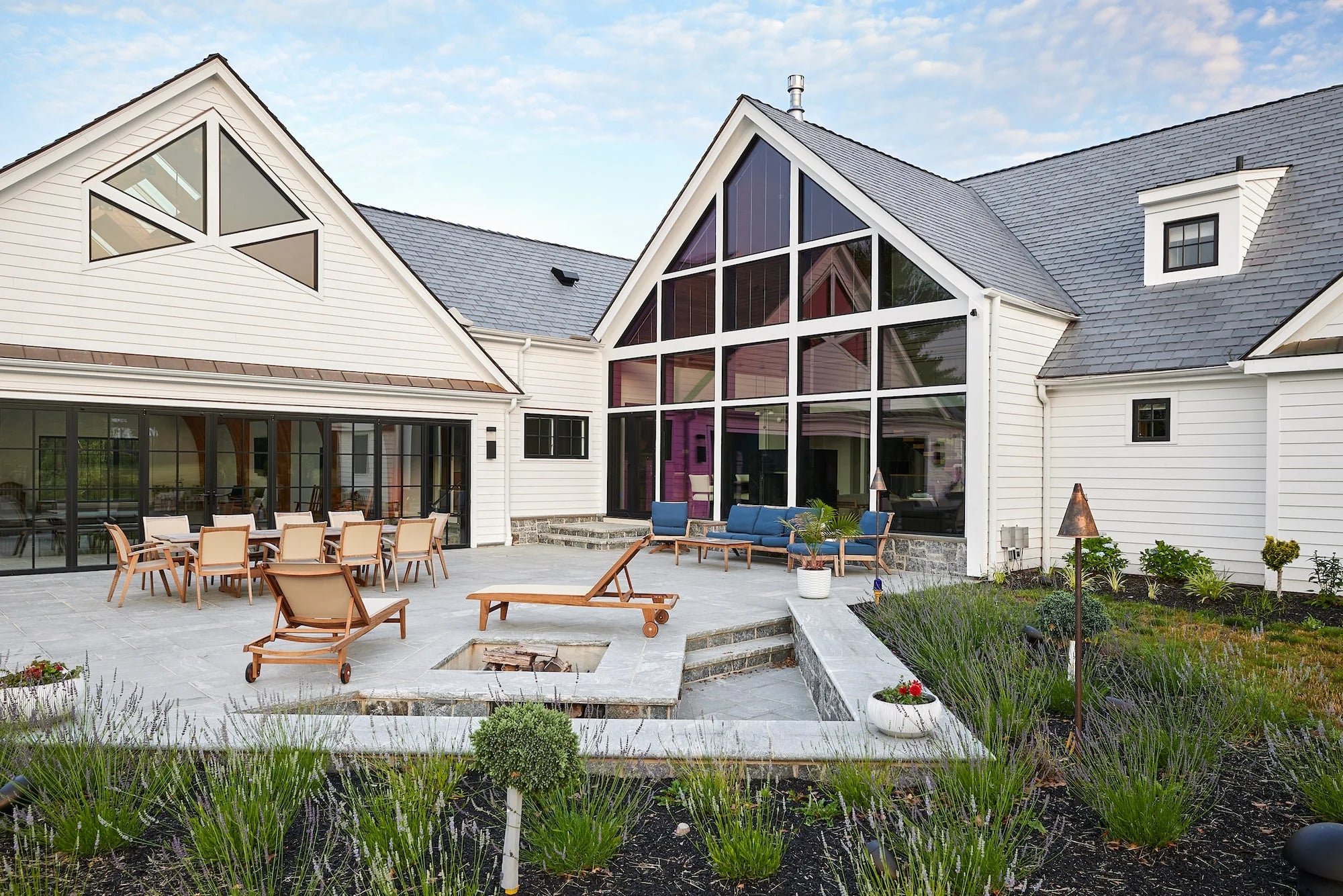 Backyard patio with fire pit, lounge chairs, and dining area outside Airport Road home