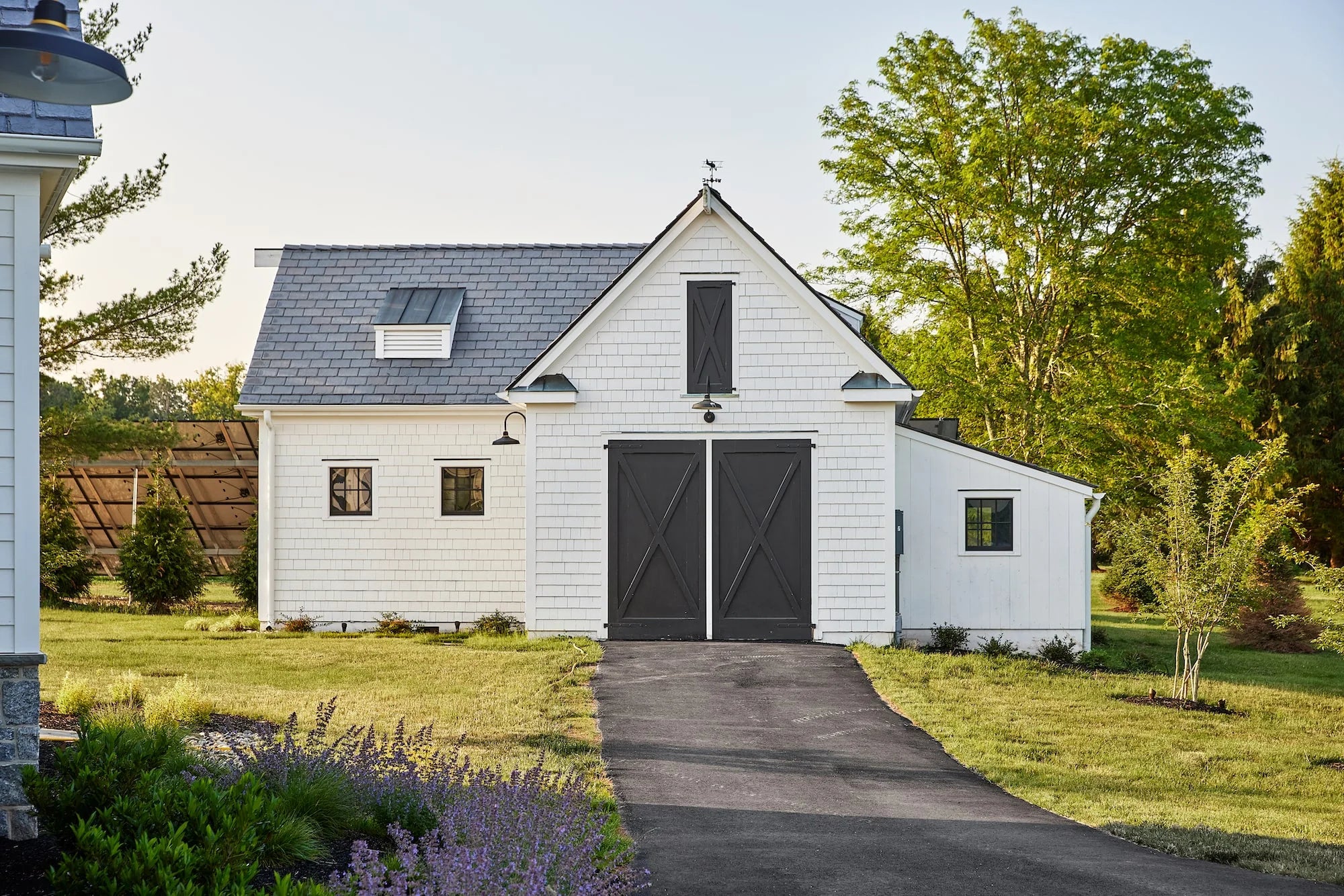 White detached garage with barn-style black doors and shingle roof at Airport Road property