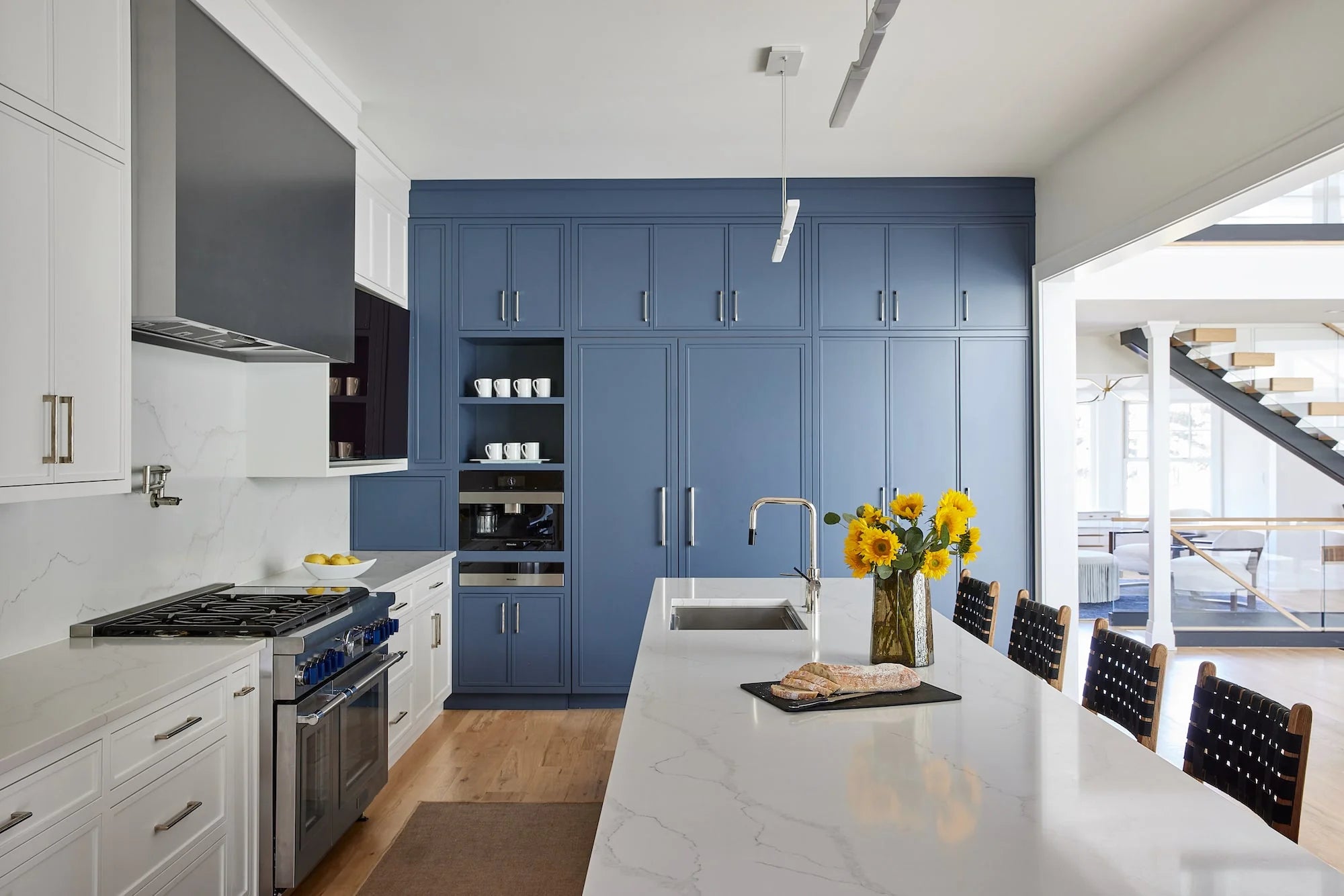Contemporary kitchen with navy blue built-in cabinetry, white marble countertops, and large island at Airport Road
